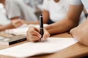 Photo of a classroom with students and a teacher. If too hard, photo of a notebook, pen, etc. to suggest assessment.