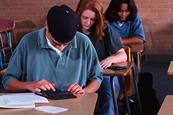 Photo of either people taking an exam or of simply a room in a school set up for an exam.