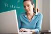 Photo of a teacher writing a paper or typing on their computer.