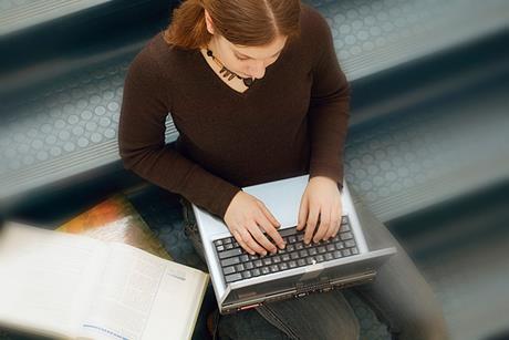 Photo of a student typing on a laptop/computer.