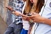 Photo of students speaking to each other and using their phones, to suggest the idea of various ways of communicating.