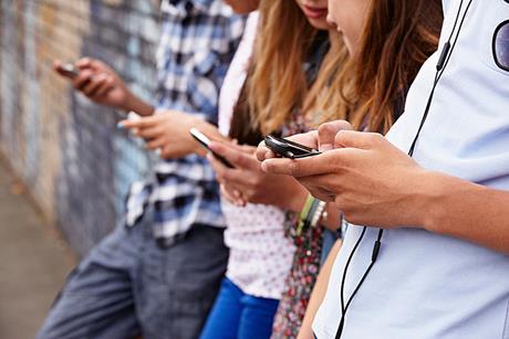 Photo of students speaking to each other and using their phones, to suggest the idea of various ways of communicating.