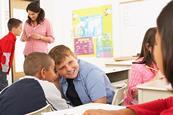 Photo of children speaking to each  other in a classroom.