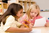 Photo of children writing in their notebook  or typing on a computer.