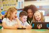 Photo of children and their teacher  working together in a classroom.