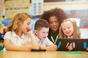 Photo of children and their teacher  working together in a classroom.