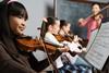 Photo of children playing different musical instruments .