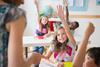 Photo of a teacher talking to their students in a classroom. (students should be children)