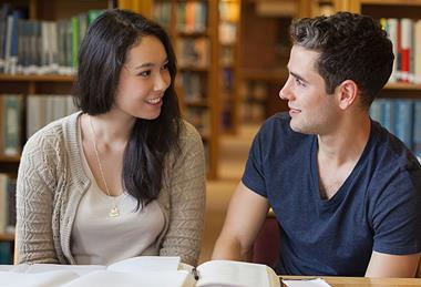 Photo of students in a classroom talking to each other.