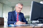 Photo of a teacher writing something. Can be on a piece of paper or on a computer.